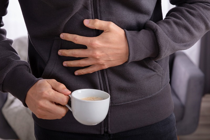 man suffering stomach pain cup coffee | people health care problem concept unhappy | what causes left side pain under ribs