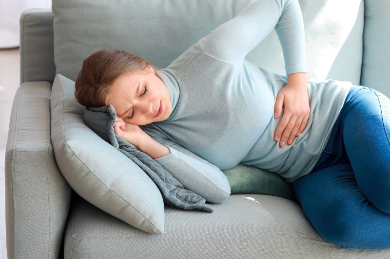 Young Woman Suffering from Stomach Ache at Home | Stomach Problems That Affect the Heart