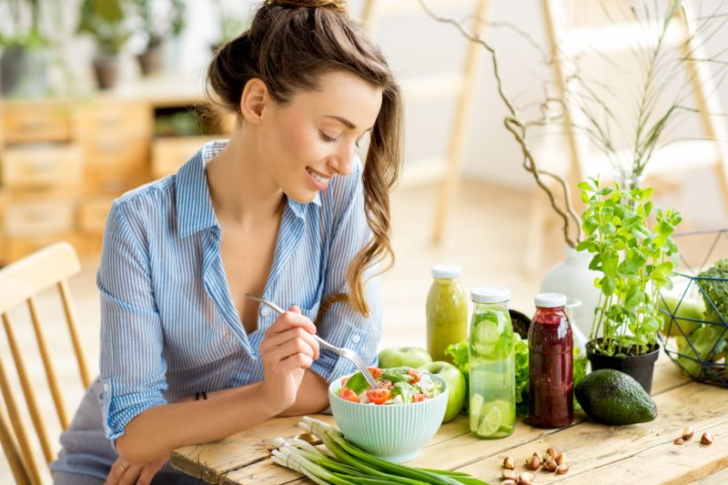 Young happy woman eating healthy salad | What to avoid after stent