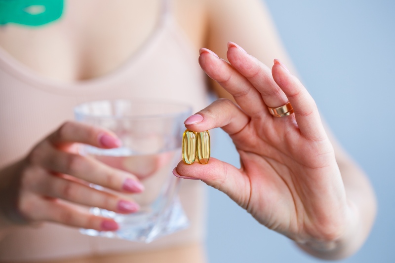 Hand with Pills Woman Takes Medicine | How Is Vitamin E Thought to Play a Role in Reducing the Risk of Heart Disease