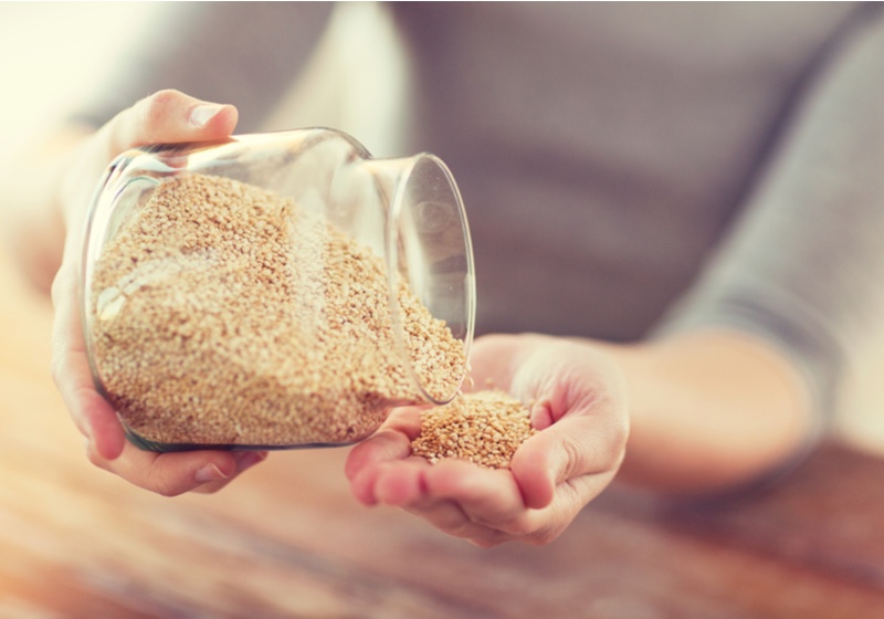 Quinoa benefits _ close up of female emptying jar with quinoa