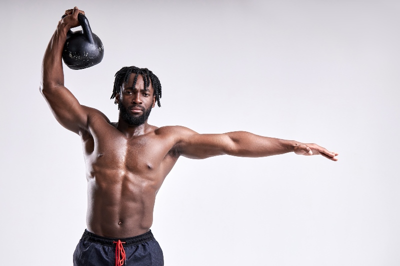 African-American Shirtless Man Lifting Kettlebell | How to Do Arnold Press