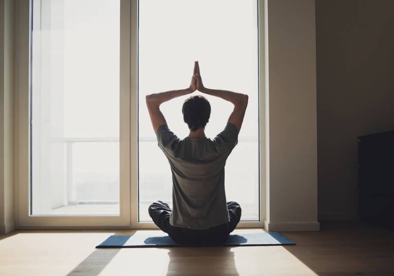 young-man-practicing-yoga-home men's self care