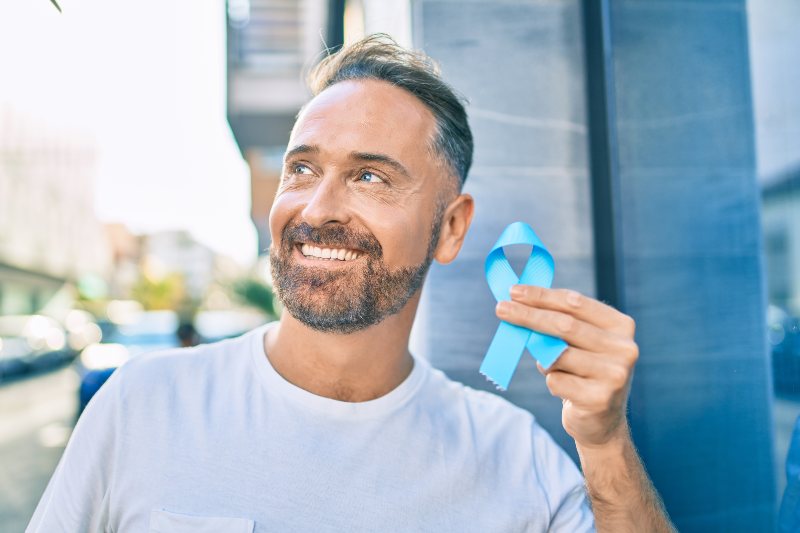 Middle age handsome man smiling happy holding blue prostate cancer ribbon | Lecithin Prostate Benefits