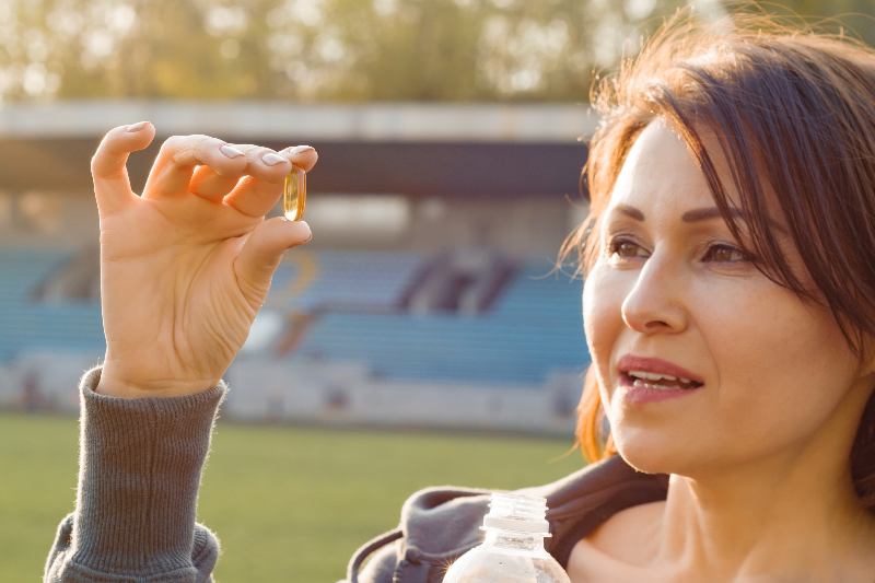 Outdoor portrait of mature woman taking vitamin E capsule pill | Is Soy Lecithin Bad for You