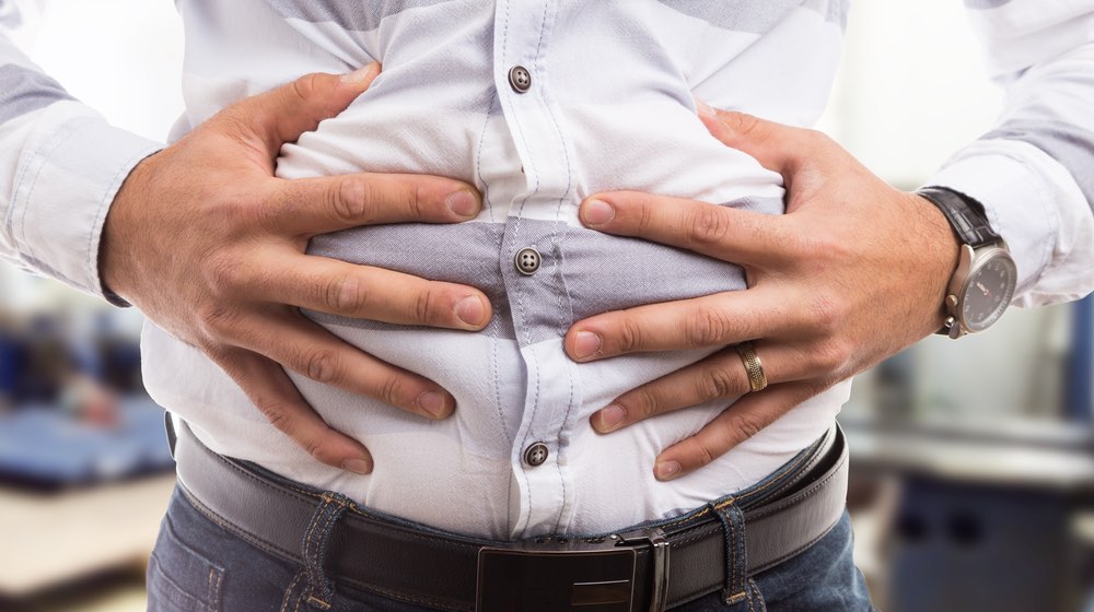 Man pressing grabbing bloated abdomen or belly as cramp flatulence constipation problem