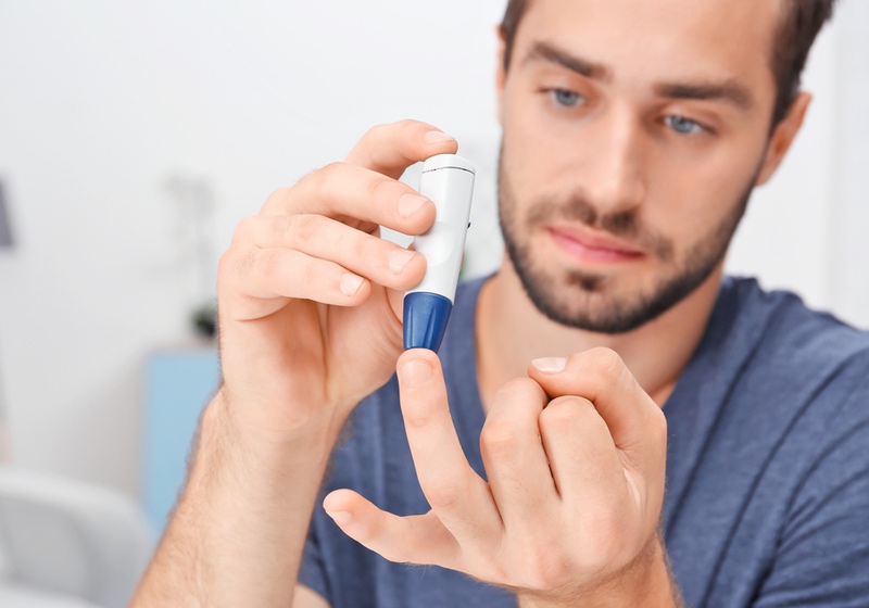 Man taking blood sample with lancet pen indoors. Diabetes