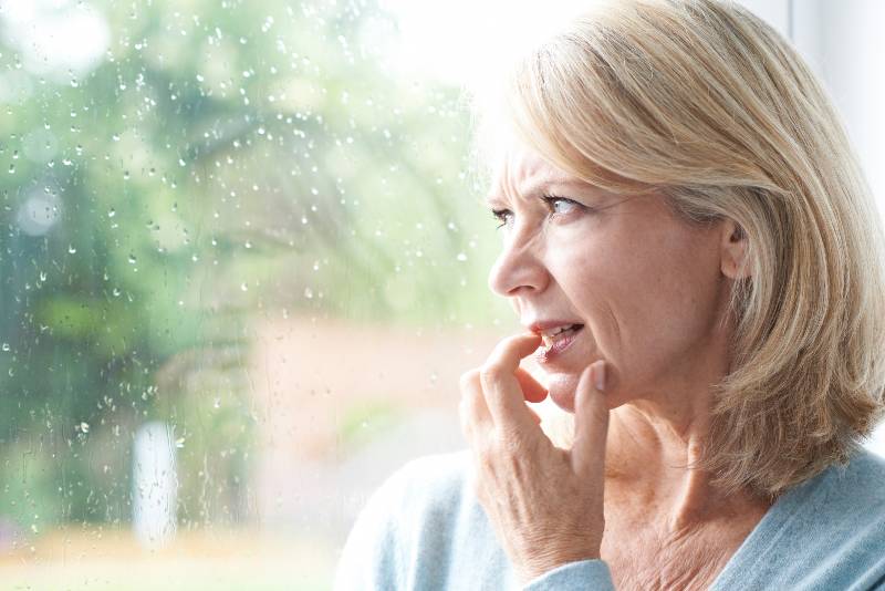 Sad Mature Woman Suffering From Agoraphobia Looking Out Of Window | Anxiety and Hot Flashes